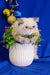 White Persian cat in festive collar sitting in a stylish white textured pot